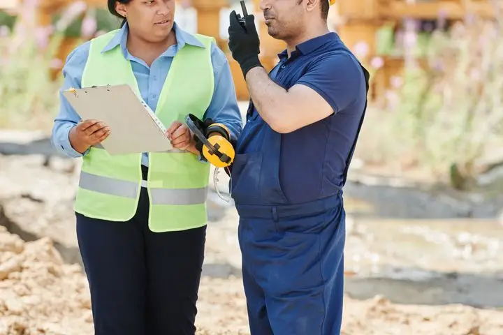 Two engineers reviewing a construction plan at a building site.