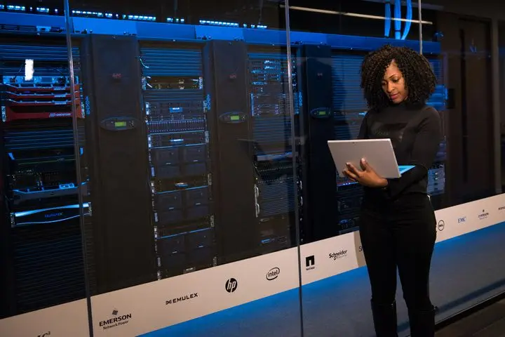 Cloud engineer monitoring server infrastructure while working on a laptop.