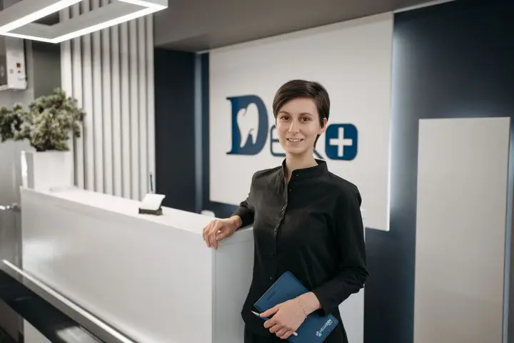 Smiling receptionist working in a modern dental clinic lobby.