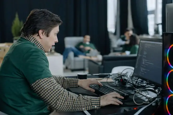 Programmer concentrating on code at a computer in a modern office.