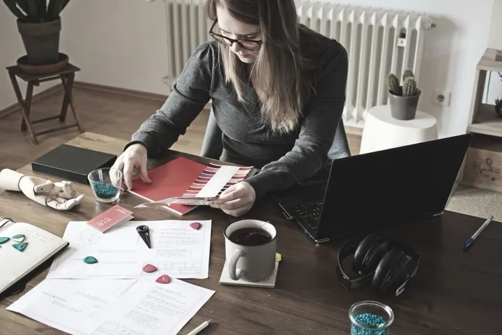 Graphic designer developing a visual concept with sketches, color swatches, and a laptop at a creative workspace.