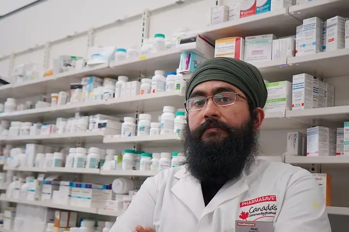 Pharmacist standing in front of organized medicine shelves.