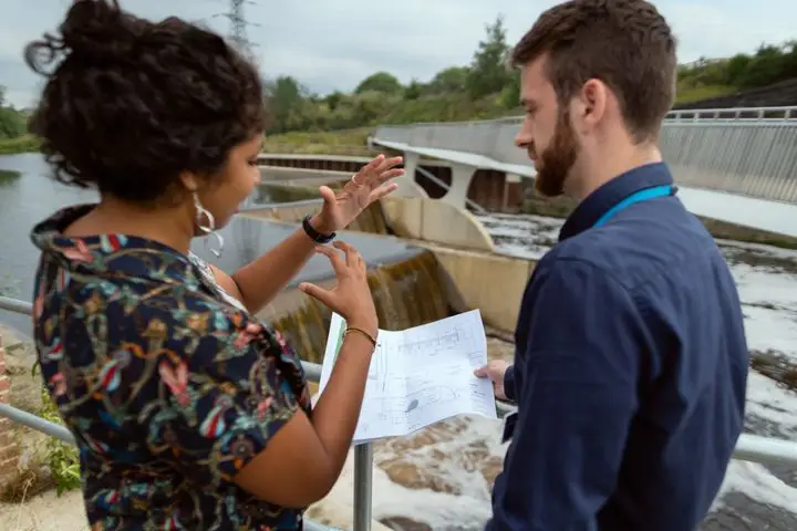 Engineers discussing project plans beside a water infrastructure site.