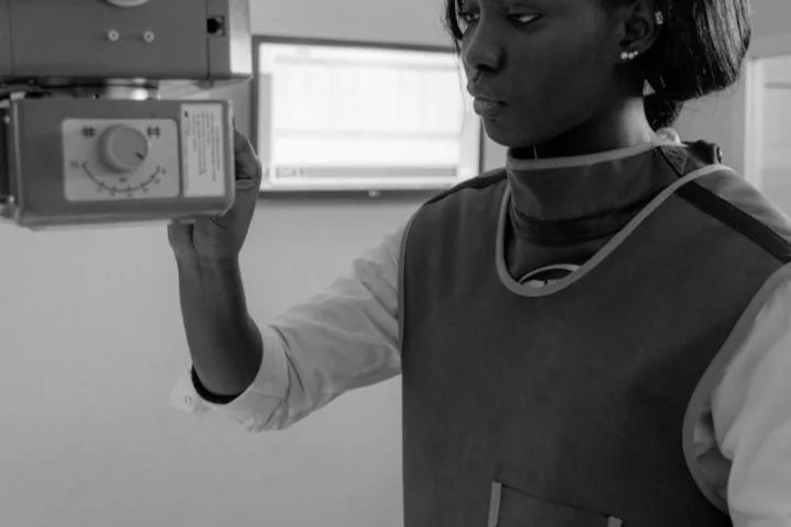 Radiologic technologist positioning diagnostic x-ray equipment in an imaging room.