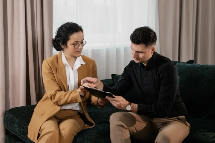 Real estate agent reviewing transaction documents with a homebuyer in a living room.
