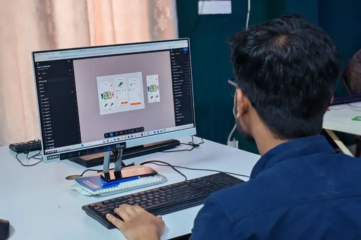 User interface designer creating a digital layout on a desktop computer.