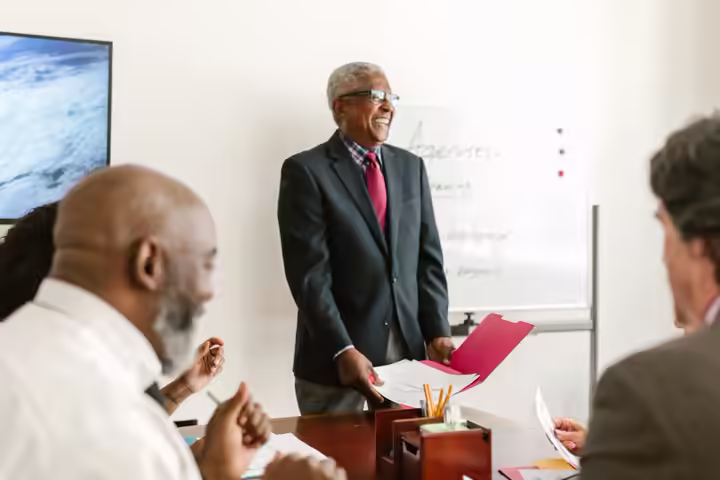 Professional meeting scene showcasing discussions and presentations in an office setting.