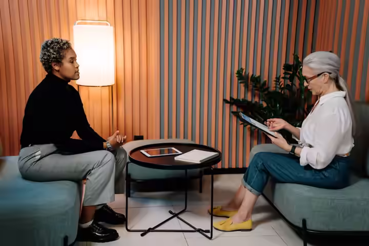 Two women engaging in a professional interview setting, using a tablet.