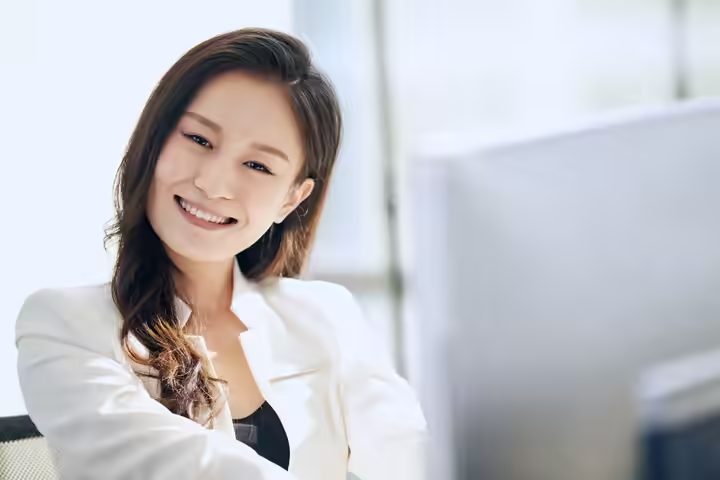 Close-up of a smiling woman in an office, conveying professionalism and positivity.