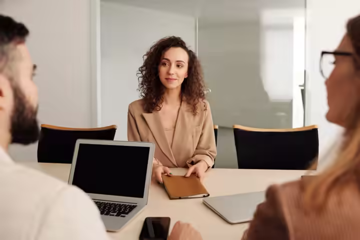 A woman in a business suit participates in a job interview, showcasing professionalism and modern office environment.