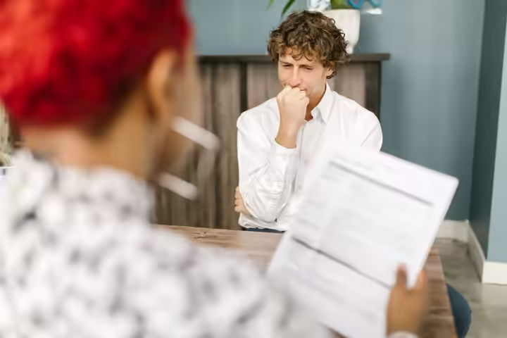 Man reflecting during a job interview in an office setting, highlighting thoughtfulness.