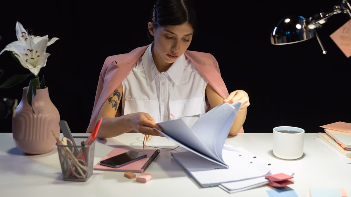 A woman reads documents at a desk in a modern office.