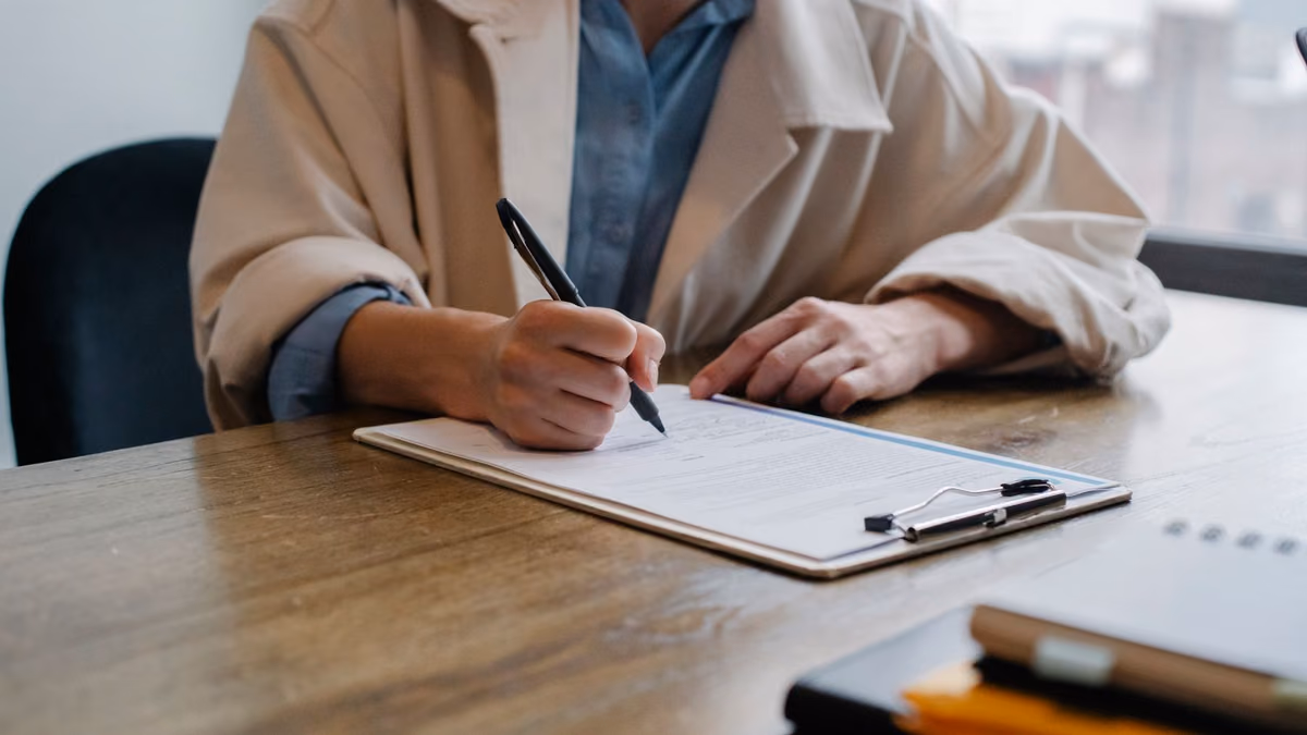 A job seeker completes paperwork at an interview table.