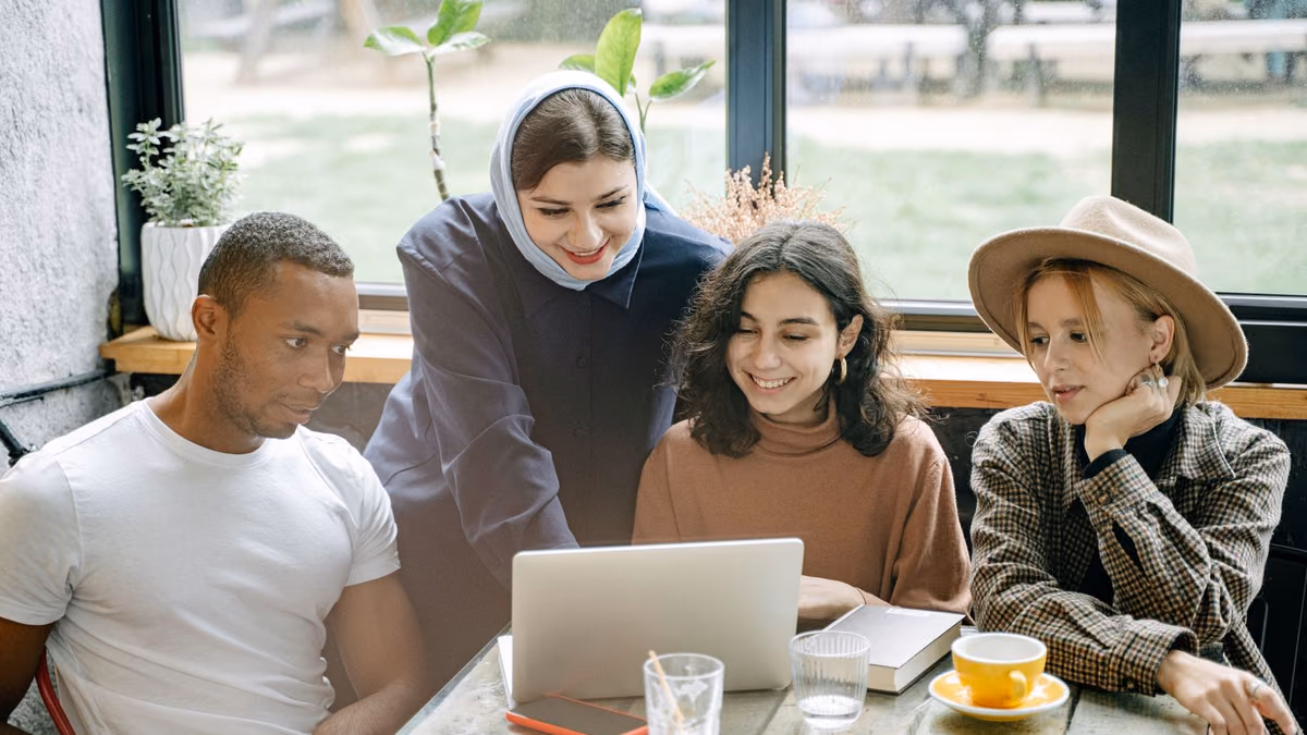 Young colleagues work together around a laptop in a bright workspace.